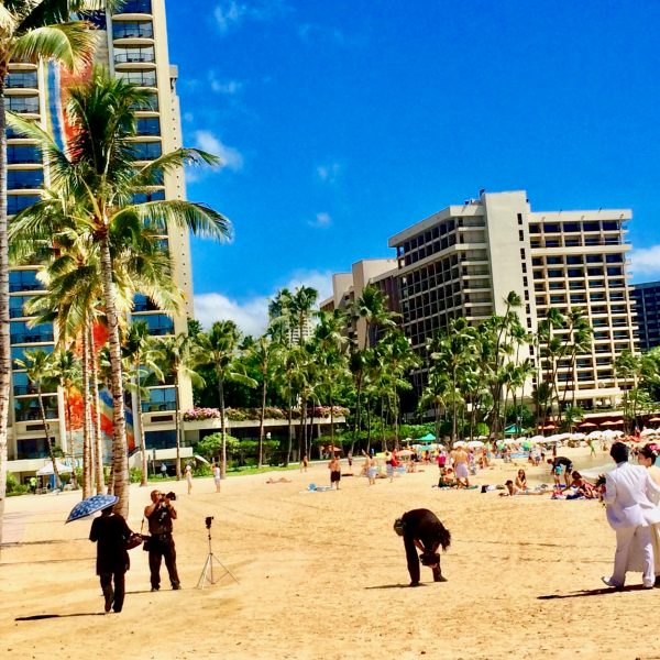 a group of people walking on a beach with a city in the background